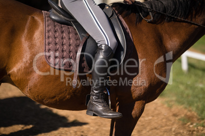 Low section of female jockey horseback riding