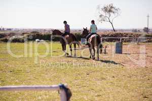 Rear view of female friends horseback riding