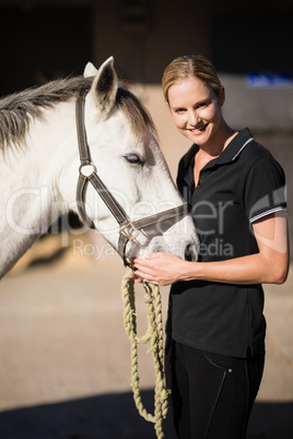 Portrait of smiling jockey stroking horse at barn