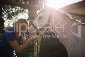 Young woman kissing horse at barn