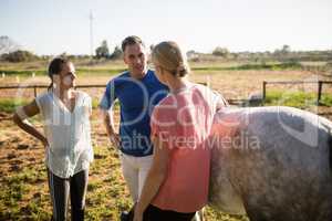 Trainer guiding women while standing by horse