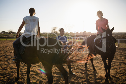Trainer guiding female friends in riding horse