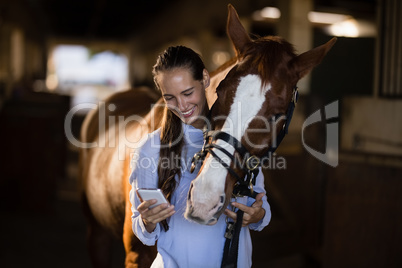 Female vet using mobile phone while standing by horse
