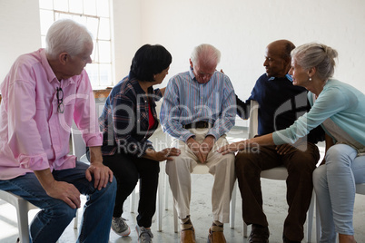 Senior friends consoling male friend