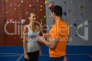 Friends talking while standing by climbing wall at gym