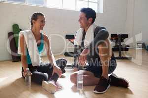 Trainer talking to athlete while relaxing in gym