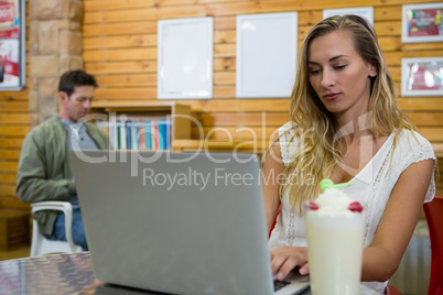 Young woman using laptop in cafe