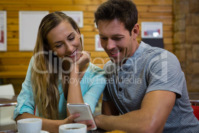 Couple using mobile phone while sitting at cafe