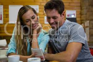 Couple using mobile phone while sitting at cafe