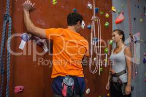 Athletes discussing while standing by climbing wall