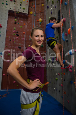 Portrait of athlete standing against trainer climbing wall at club