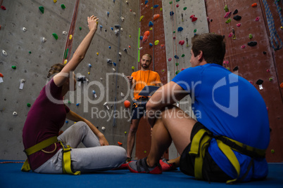 Low angle view of trainer interacting with athletes sitting on floor