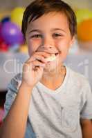 Cute boy eating sweet food during birthday party