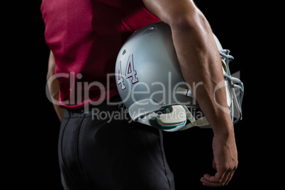 American football player holding a head gear under his arms