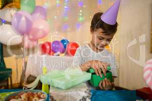 Boy opening a gift box during birthday party
