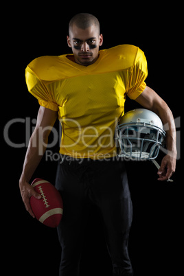 American football player holding a ball and head gear