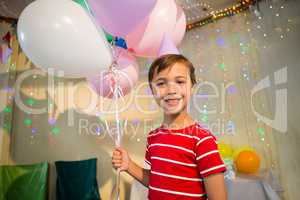 Cute boy holding balloon during birthday party