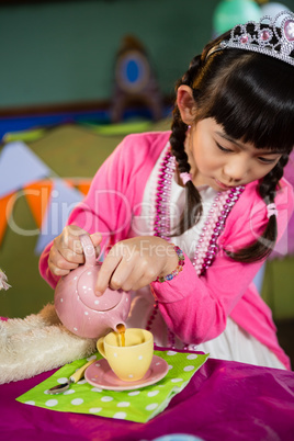 Girl pouring coffee into cup during birthday party