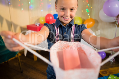 Girl holding a gift bag during birthday party hat