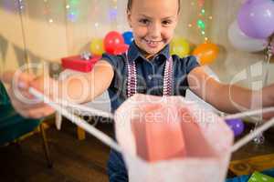 Girl holding a gift bag during birthday party hat