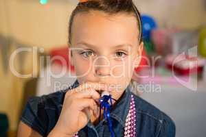 Girl blowing party horn during birthday party