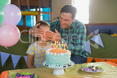 Father closing his daughters eyes during birthday party
