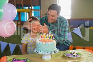 Father closing his daughters eyes during birthday party