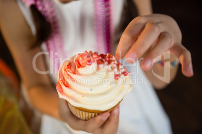 Mid section of girl decorating cupcake during birthday party