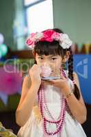 Portrait of cute girl drinking tea during birthday party