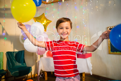 Happy boy holding balloons during birthday party