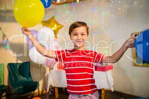 Happy boy holding balloons during birthday party