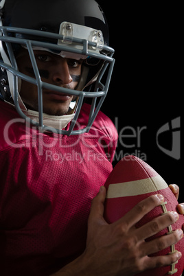 American football player holding a football with both his hands