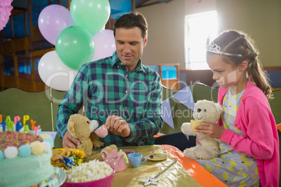 Father and girl playing toy kitchen set