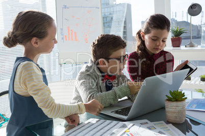 Business people discussing over technology at desk