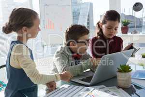 Business people discussing over technology at desk