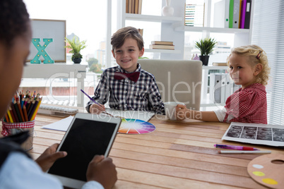 Businessman using digital tablet while discussing with colleagues in office