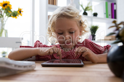 Businesswoman using digital tablet while sitting at table in office