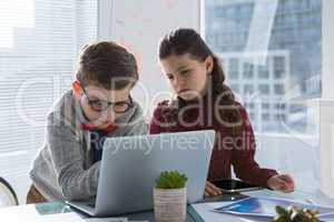 Business people discussing over laptop in office