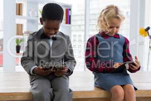 Colleagues using digital tablets while sitting on table in creative office