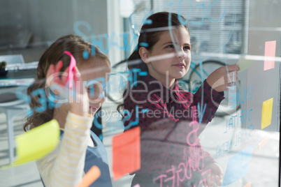 Female coworkers anlayzing data seen through glass