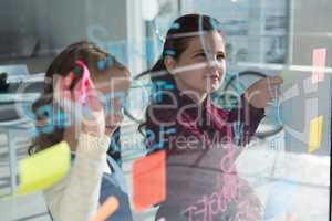 Female coworkers anlayzing data seen through glass