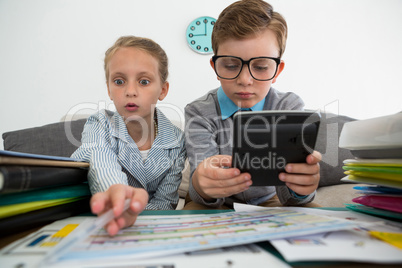 Businessman using digital tablet while female colleague analyzing files