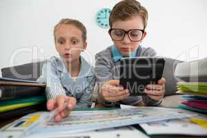 Businessman using digital tablet while female colleague analyzing files