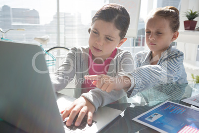 Female coworkers discussing over laptop at desk