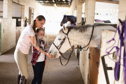 Smiling sisters feeding horse