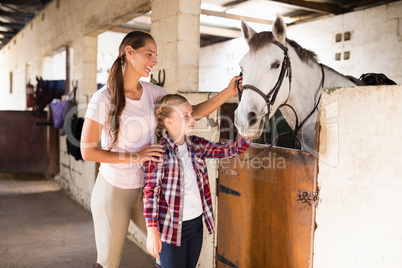 Smiling sisters stroking horse
