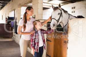 Smiling sisters stroking horse