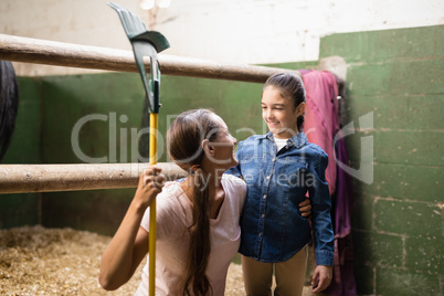 Smiling female jockey holding rake while talking to sister