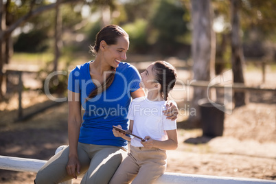 Smiling sisters talking while sitting on railing