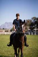 Portrait of confident jockey riding horse at barn